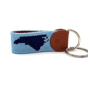 Peut inclure: Un porte-cl&eacute;s bleu clair et bleu marine avec une sangle en cuir et un anneau en m&eacute;tal. Le porte-cl&eacute;s repr&eacute;sente le contour de l'&eacute;tat de Caroline du Nord.