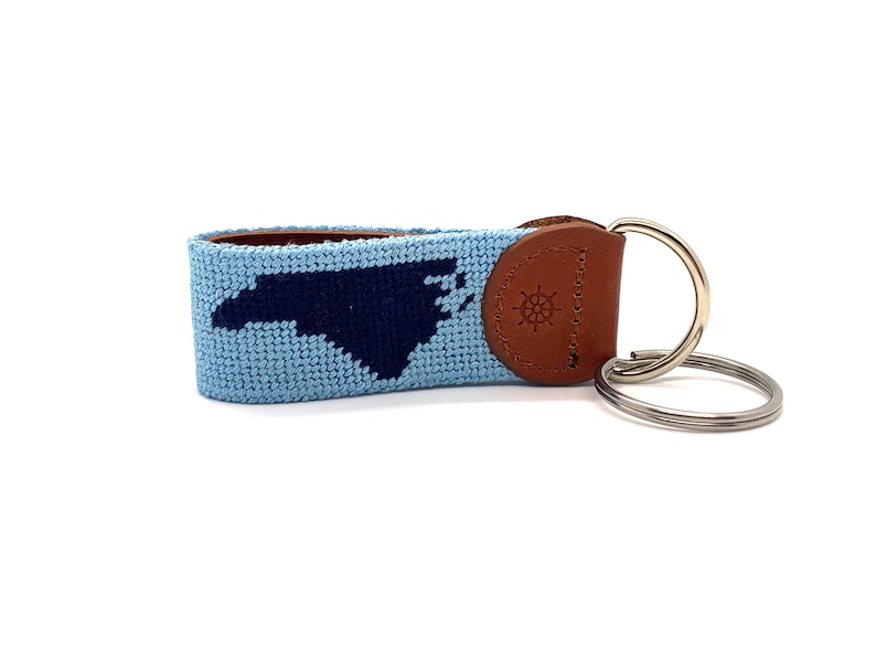 Peut inclure: Un porte-cl&eacute;s bleu clair et bleu marine avec une sangle en cuir et un anneau en m&eacute;tal. Le porte-cl&eacute;s repr&eacute;sente le contour de l'&eacute;tat de Caroline du Nord.