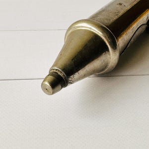 Close-up of the metal nozzle tip on a French vintage grease pump, antique Perolin lubrication tool with patina and mechanical details