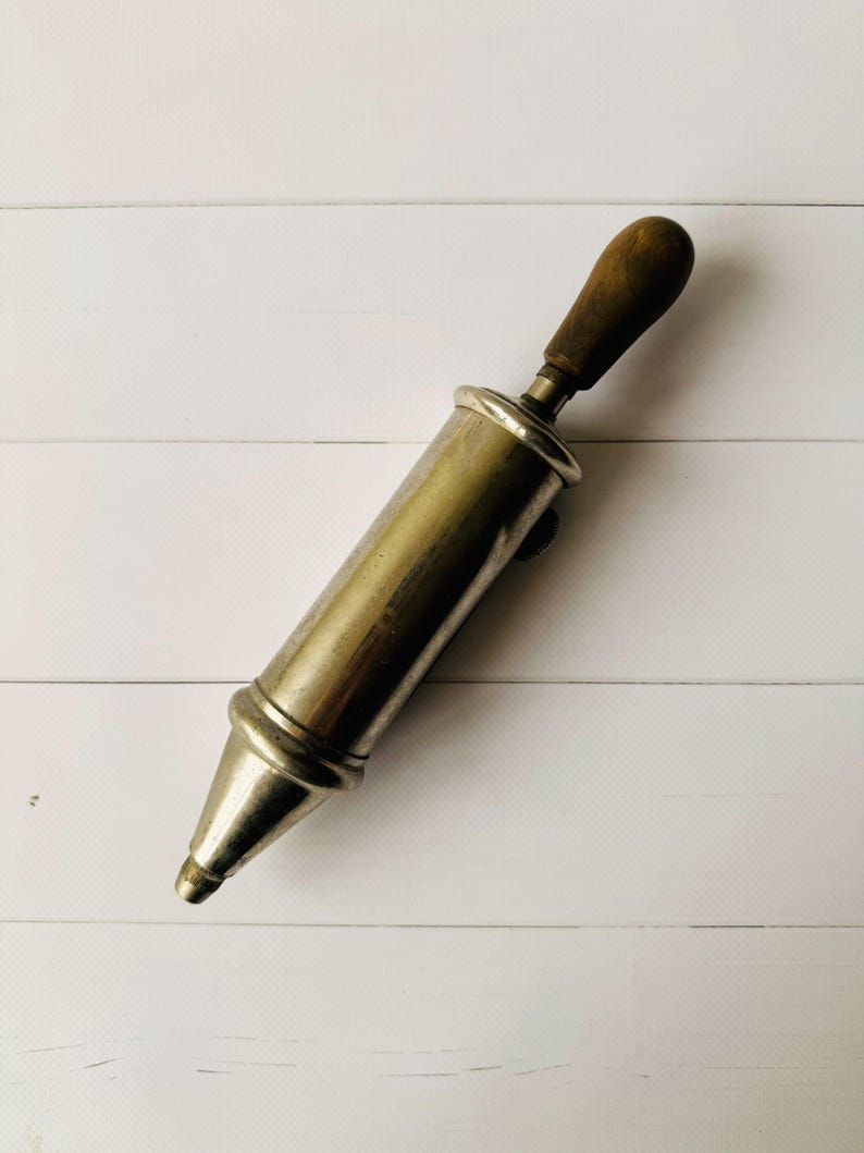 French vintage grease pump Perolin photographed vertically, metal lubrication tool with wooden handle, suitable as steampunk decor or mechanic gift