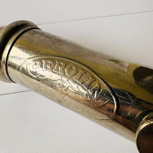 Detailed view of the Perolin logo plate on a French vintage lubrication tool, antique grease pump with visible signs of age and use