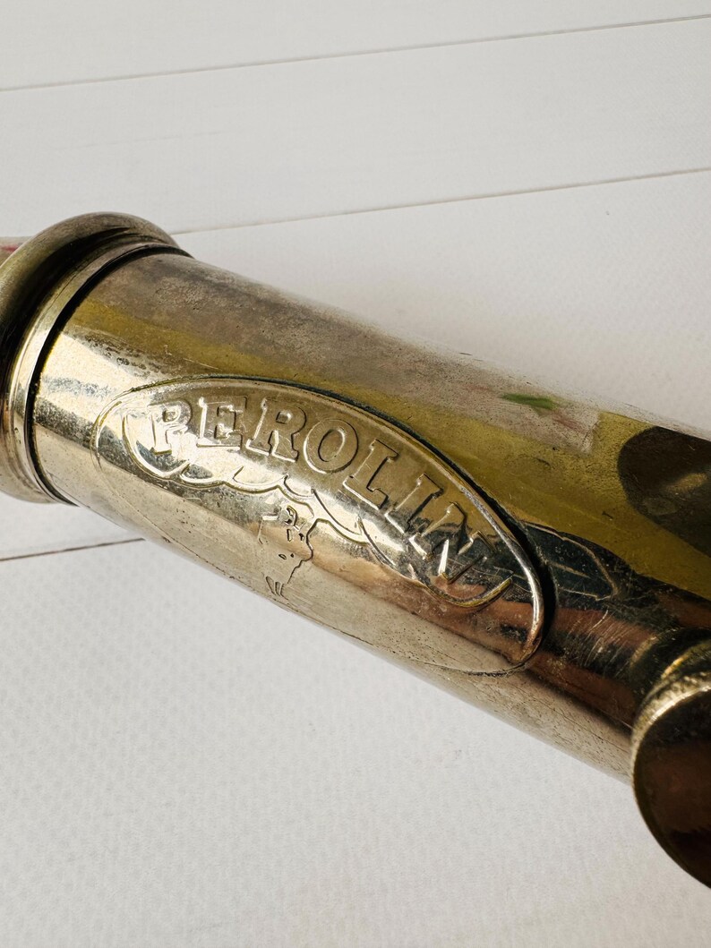 Detailed view of the Perolin logo plate on a French vintage lubrication tool, antique grease pump with visible signs of age and use