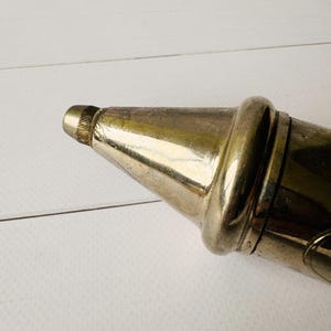 Close-up of the metal nozzle on an antique grease pump, vintage Perolin lubrication tool with worn metal finish