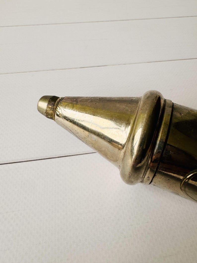 Close-up of the metal nozzle on an antique grease pump, vintage Perolin lubrication tool with worn metal finish