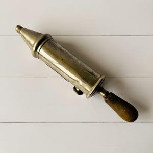 French vintage lubrication tool Perolin displayed diagonally, antique grease pump with metal body, suitable as steampunk decor or garage decor