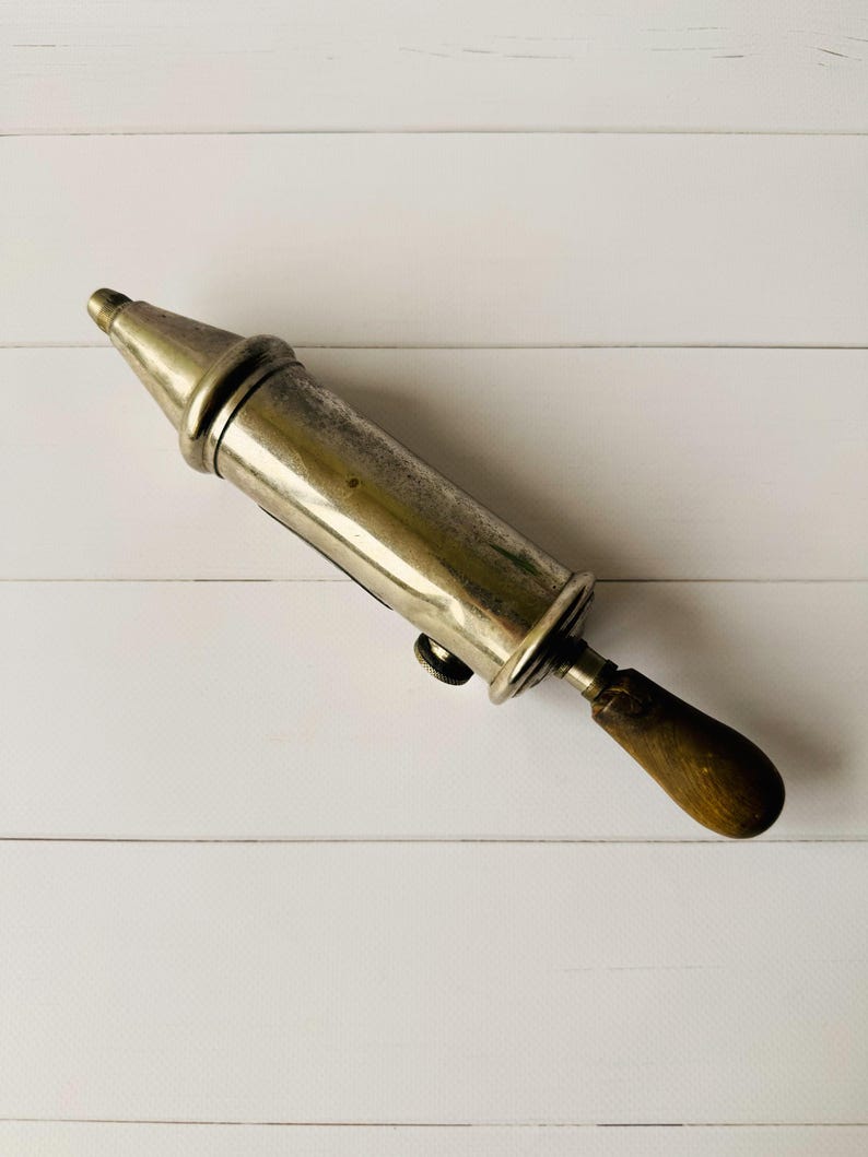 French vintage lubrication tool Perolin displayed diagonally, antique grease pump with metal body, suitable as steampunk decor or garage decor