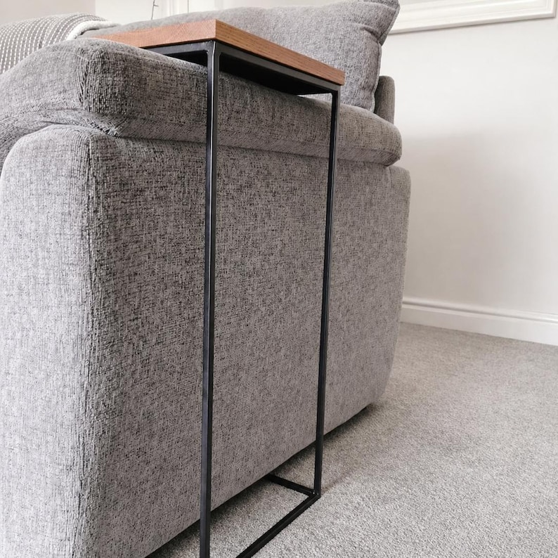 Pu&ograve; includere: Un tavolino moderno con un piano rettangolare in legno marrone chiaro e una struttura in metallo nero. Il tavolino &egrave; progettato per essere posizionato accanto a un divano. Le dimensioni del tavolino sono di circa 71 cm di altezza, 25 cm di larghezza e 46 cm di profondit&agrave;.