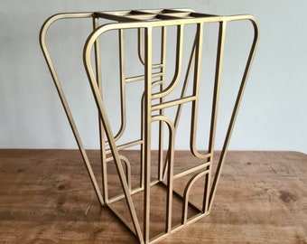 May include: A gold metal stand with a geometric design. The stand is made of thin metal rods that are welded together to create a unique and modern look.