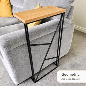 May include: A side table with a light wood top and a black geometric metal frame. The table is designed to slide alongside a sofa. The text "Geometric Art Deco Design" is in the bottom right corner.