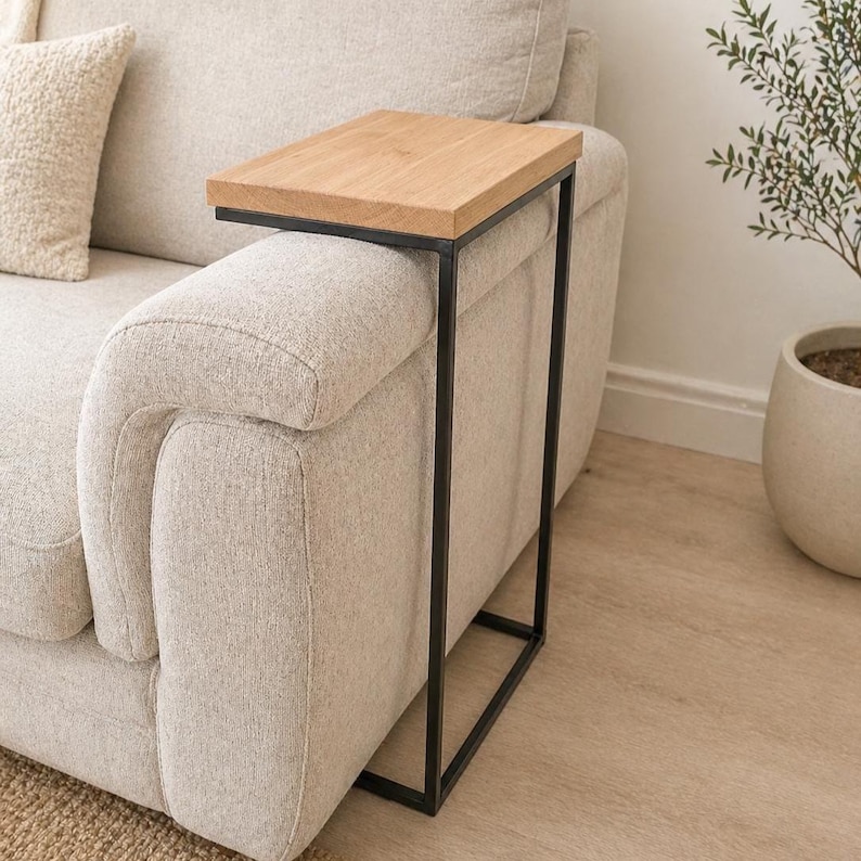 Pu&ograve; includere: Un tavolino con piano in legno chiaro e struttura in metallo nero. Il tavolino &egrave; progettato per essere posizionato sul bracciolo di un divano. Il piano del tavolo misura circa 40 cm di lunghezza e 30 cm di larghezza.