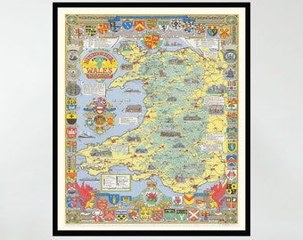 May include: A framed vintage map of Wales with a colorful design featuring coats of arms and other details. The map is surrounded by a black frame and is hanging on a white wall above a gray couch.
