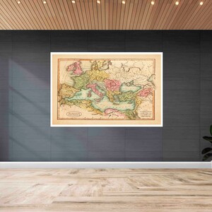 May include: A vintage map of the Roman Empire, printed on paper with a cream background. The map is framed and hanging on a dark gray wall.
