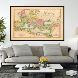 May include: A vintage map of the Roman Empire, framed in black, with a light brown background and colorful markings. The map shows the extent of the Roman Empire at its peak, with various regions and provinces highlighted in different colors.