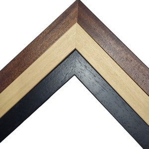 May include: Close-up of a corner of a picture frame with three layers of wood. The outer layer is a dark brown wood, the middle layer is a light brown wood, and the inner layer is a black wood.