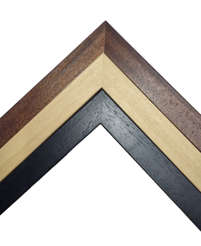 May include: Close-up of a corner of a picture frame with three layers of wood. The outer layer is a dark brown wood, the middle layer is a light brown wood, and the inner layer is a black wood.