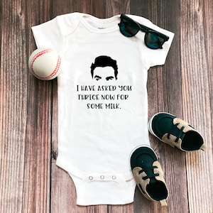 May include: White baby onesie with a black and white illustration of a man's face and the text "I have asked you thrice now for some milk."