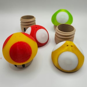 May include: Four mushroom-shaped containers with different coloured tops. The tops are red, yellow, green, and brown. The containers are made of wood and have a smooth finish.