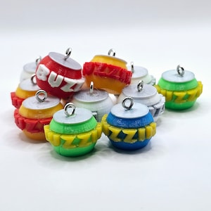 May include: A collection of nine colorful ornaments with the word "Buzz" printed on them. The ornaments are made of plastic and have a shiny finish. They are all different colors, including red, yellow, blue, green, and white.