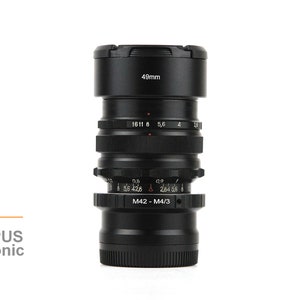 May include: A black MIR-1V Soviet lens with a 49mm filter thread. The lens has a M42 to M4/3 adapter and is compatible with Olympus and Panasonic cameras.