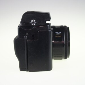 May include: A black 35mm film camera with a 50mm color lens. The camera has a black body and a black lens with gold lettering that reads "COLOR LENS 50mm".