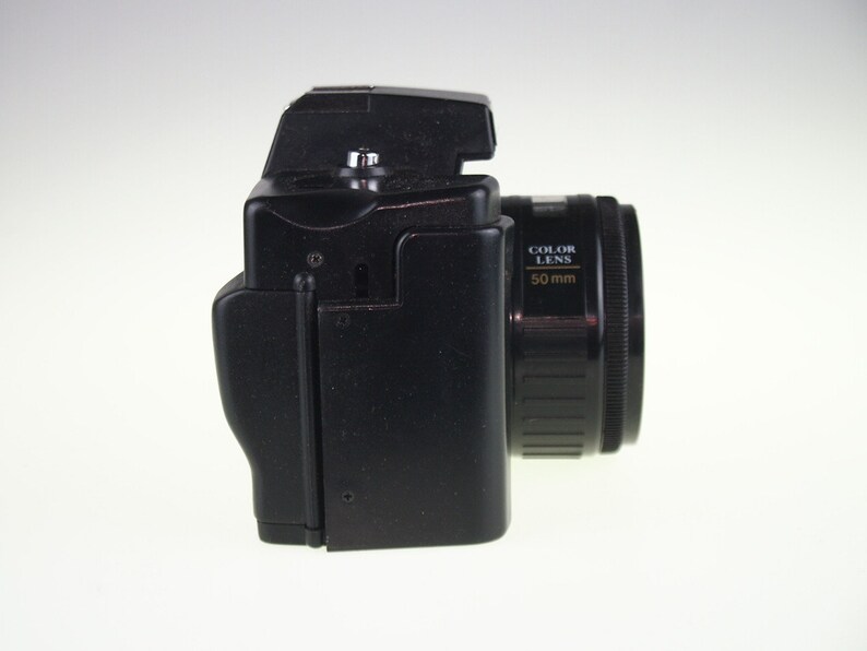 May include: A black 35mm film camera with a 50mm color lens. The camera has a black body and a black lens with gold lettering that reads "COLOR LENS 50mm".