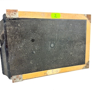 May include: Rectangular, vintage-style speaker with a black perforated front and a wooden frame. The frame has metal corner brackets and a green sticker with the number 2. The speaker's dimensions are approximately 13 inches by 15 inches.