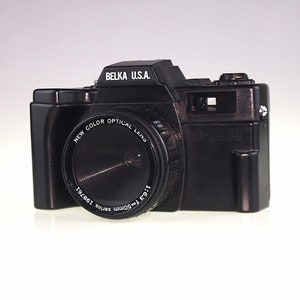 May include: A black Belka U.S.A. 35mm film camera with a New Color Optical lens. The lens has the text "1:6.3 f-50mm series 198761" printed on it.