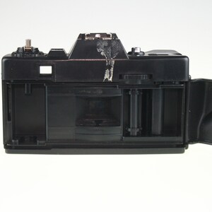 May include: A black 35mm film camera with the back open, revealing the film compartment and a roll of film.