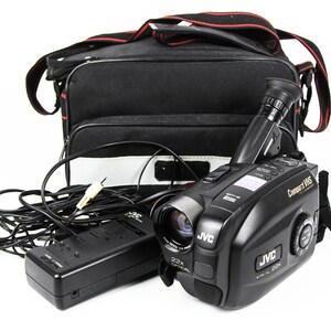 May include: A black JVC Compact VHS camcorder with a 22x optical zoom lens, a black carrying case, and a black power adapter.
