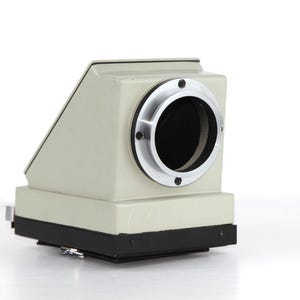May include: A gray camera body with a black lens and a silver lens ring. The camera has a rectangular shape and a black base.
