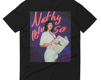May include: A black t-shirt with a graphic print of a woman holding a newspaper. The text "Nathy Peluso" is written in red on the graphic.