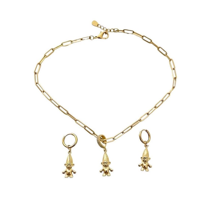 May include: A gold-toned jewelry set consisting of a paperclip chain necklace and two matching hoop earrings. Each piece features a small, three-dimensional troll figurine charm. The necklace clasp includes a small, clear stone accent.