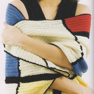 May include: A woman wearing a black sleeveless top with a colorful crocheted shawl. The shawl is made of different colored squares in blue, red, yellow, white, and black.