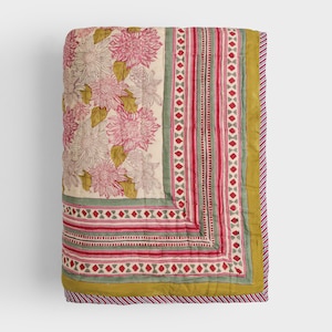 May include: A floral quilt with large pink and white flowers on an off-white background. The quilt has a striped border with red and green accents, and a green border. The edges are finished with a striped pattern.