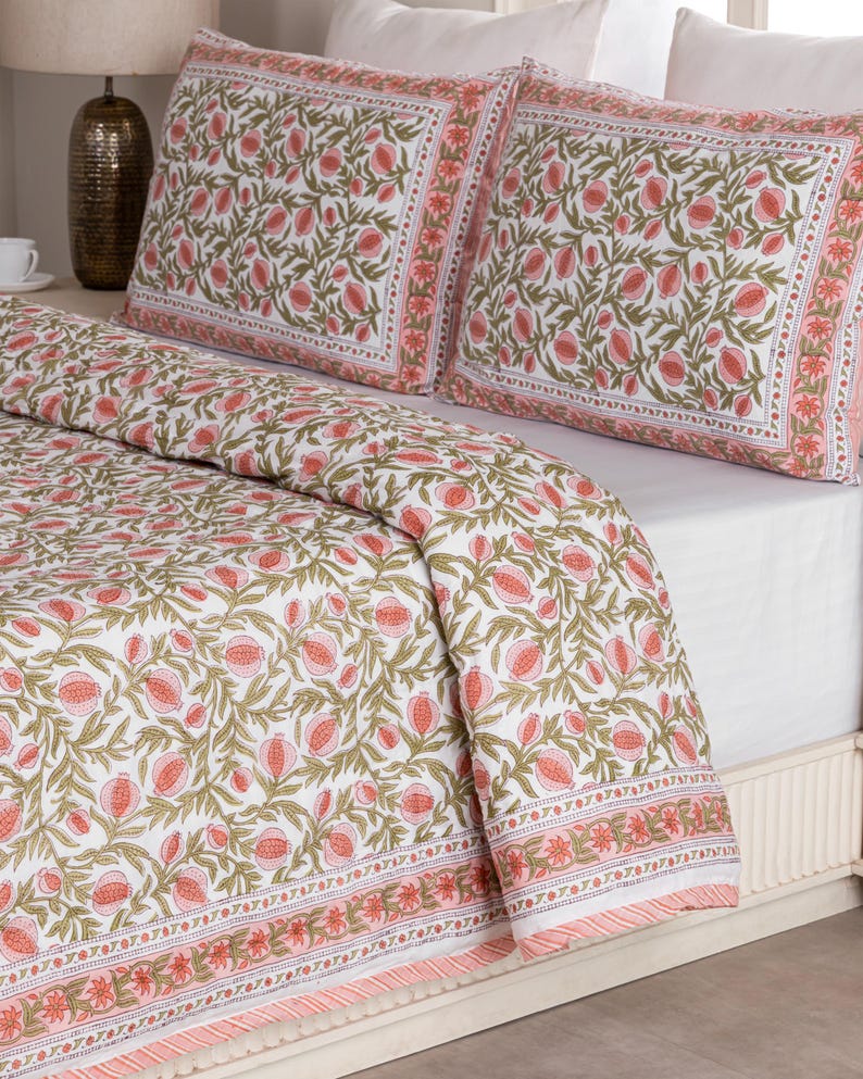 May include: White bedding set with a floral pattern in shades of pink and green. The set includes a comforter and two pillowcases. The floral design is repeated across the entire set, with a border of pink and white stripes.