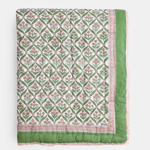 May include: A floral patterned quilt featuring a repeating design of pink flowers and green leaves on a white background. The quilt has a green border and a pink and white striped edge. The overall design is symmetrical and visually appealing.