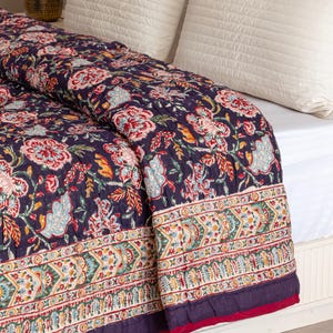 K&ouml;nnte beinhalten: Eine dunkelblaue Blumenbettw&auml;sche mit wei&szlig;em Rand und rotem Saum. Die Bettw&auml;sche ist aus Baumwolle und hat ein handgen&auml;htes Design.