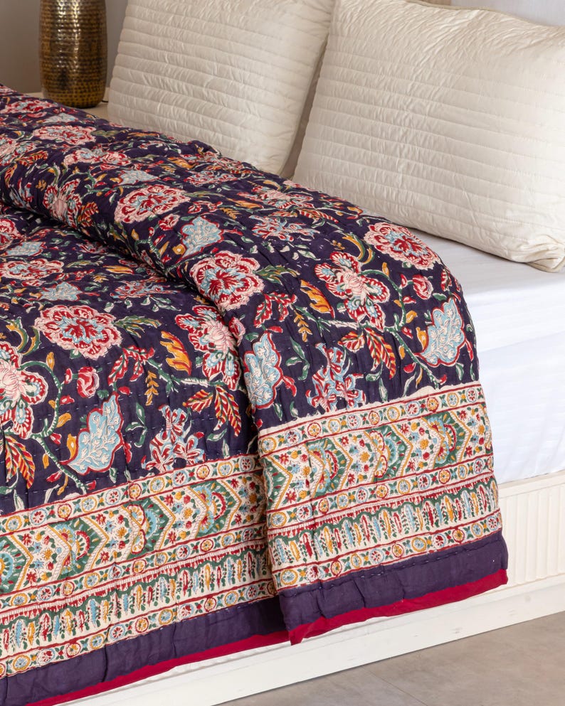 K&ouml;nnte beinhalten: Eine dunkelblaue Blumenbettw&auml;sche mit wei&szlig;em Rand und rotem Saum. Die Bettw&auml;sche ist aus Baumwolle und hat ein handgen&auml;htes Design.
