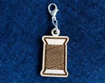 Marcador de puntadas de madera con cierre de mosquetón y canilla de hilo.