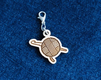 Wooden stitch marker with lobster clasp featuring a ball of yarn with a crochet hook