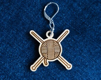 Marcador de puntadas de madera con cierre de palanca con ovillo de hilo y agujas de tejer.