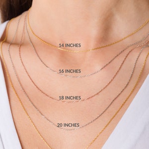 May include: Five gold chains of different lengths, 14 inches, 16 inches, 18 inches, 20 inches, and 22 inches, are shown on a model's neck. The chains are all the same style, with a delicate, cable-link design.