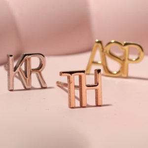 Pode incluir: Três brincos de iniciais de ouro, um par é de prata, um par é de ouro rosa e um par é de ouro amarelo. Os brincos soletram as letras "KR", "TH" e "ASP".