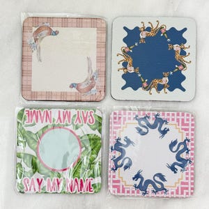 May include: Set of four square coasters with various designs. One features pheasants, another has leopard print, a third says "SAY MY NAME", and the last has blue dragons. Each coaster is packaged in clear plastic.