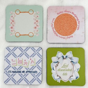 May include: Set of four square coasters with various designs. One has a floral frame and equestrian-themed accents. Another features a textured circle with the text "Baby, that's Mahjong for you." The third has Chinese characters and the text "IT'S MAHJONG WE APPRECIATE!" The last has a bow and the text "Last discarded tile."