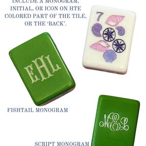 May include: Three double-sided tiles. Two green tiles with white monograms, one with a fishtail monogram and the other with a script monogram. The third tile is white with a number 7, seashells, and compass rose designs. Text: DOUBLE SIDED TILES INCLUDE A MONOGRAM, INITIAL, OR ICON ON THE COLORED PART OF THE TILE, OR THE 'BACK'.