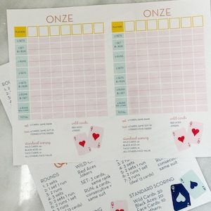 May include: Game score sheets with the word "ONZE" at the top. The sheets have spaces for players and scoring, with details on sets, runs, and wild cards. Playing card illustrations are included.