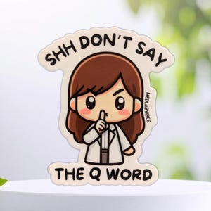Könnte beinhalten: Ein gestanzter Aufkleber mit einer Cartoon-Figur mit braunen Haaren in einem weißen Laborkittel, die einen Finger zum Schweigen auf die Lippen legt. Der Text SHH DON'T SAY THE Q WORD steht in schwarzen Großbuchstaben auf cremefarbenem Grund.