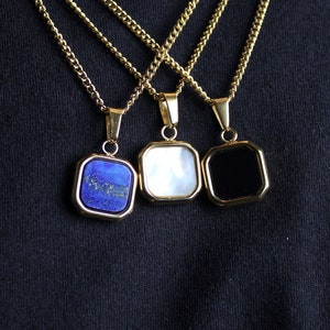 May include: Three gold chains with square pendants. The pendants are blue, white, and black.
