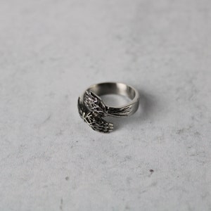 May include: A silver ring with two hands clasped together, forming a circle.